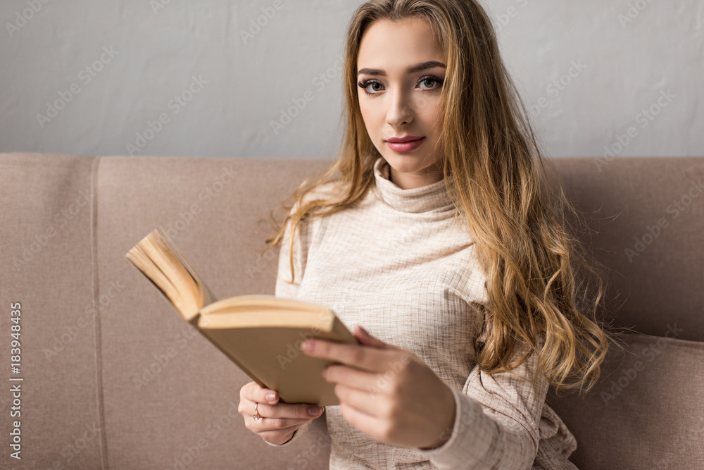 attractive young woman reading book on couch attractive young woman reading book on couch