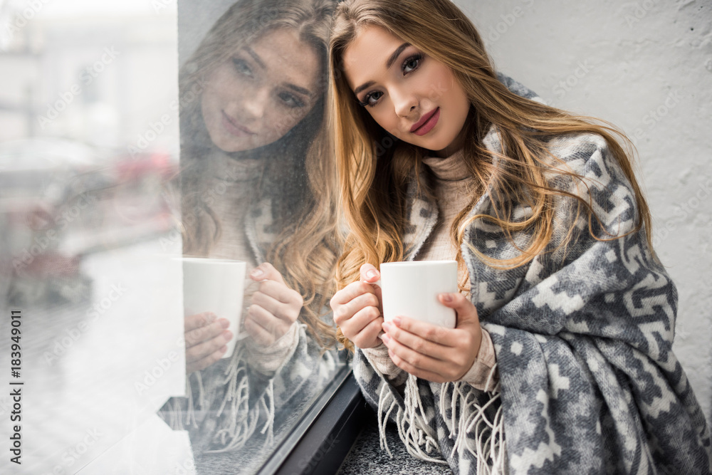 beautiful young woman drinking coffee while leaning on window beautiful young woman drinking coffee while leaning on window