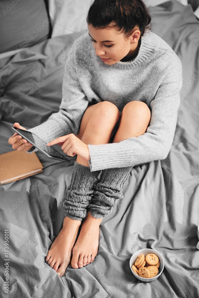 Girl sitting on bed in morning and using tablet Girl sitting on bed in morning and using tablet