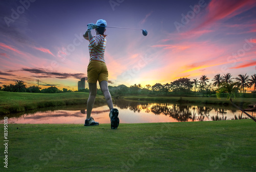 a woman golf player in an action of ene of downswing after hit the golf ball away from tee off to the fairway ahead by wood driver photo