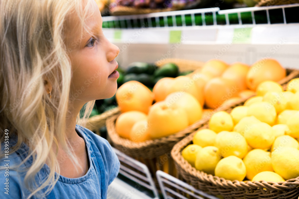 adorable female child choosing fruits in supermarket adorable female child choosing fruits in supermarket