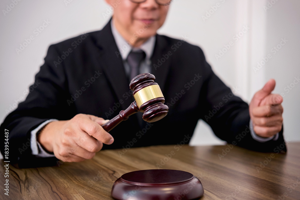 Male lawyer or judge hand's striking the gavel on sounding block, working at courtroom, Law and justice concept Male lawyer or judge hand's striking the gavel on sounding block, working at courtroom, Law and justice concept