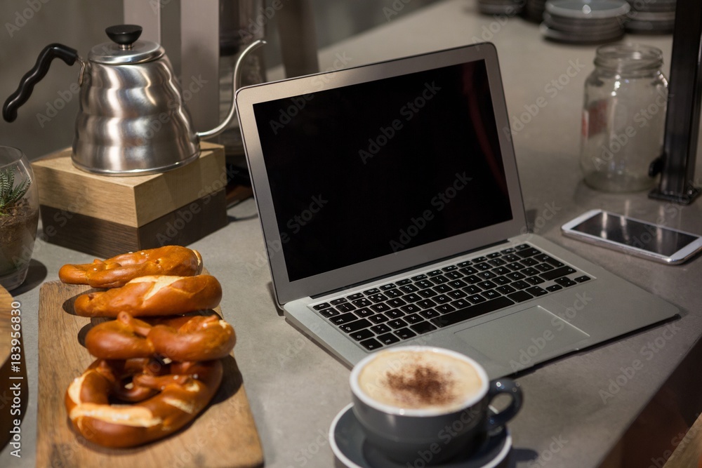 Close-up of coffee, laptop and pretzel at counter Close-up of coffee, laptop and pretzel at counter