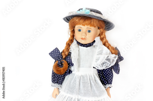 An old doll in a hat. Beautiful porcelain doll in a dress on a white background.