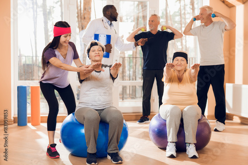 A group of elderly women and men doing therapeutic gymnastics in a nursing home.