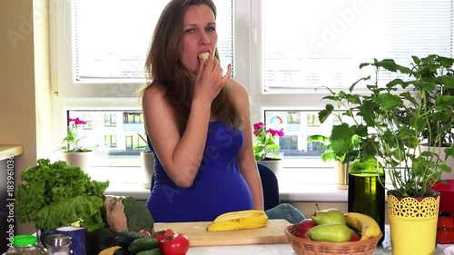 Pregnancy time nutrition. Pregnant woman eat banana sitting near kitchen table