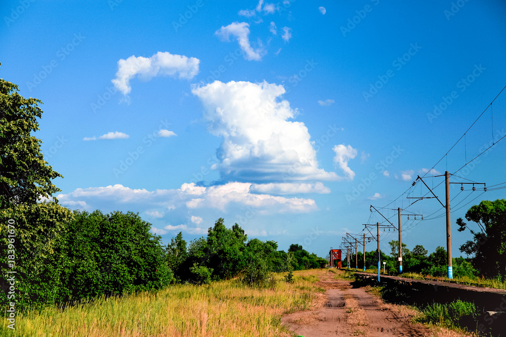 the railroad goes into the distance against a blue sky with clouds