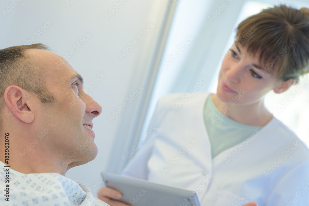 Fototapeta premium female doctor consulting patient lying on hospital bed