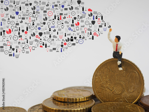 Miniature businessman sitting on Euro coin and drawing business icons on white background. Business and finance concept.