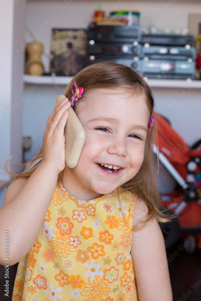 Portrait of three years old child indoors, with yellow dress, listening smartphone mobile in her hand in ear, laughing with happy expression face
Portrait of three years old child indoors, with yellow dress, listening smartphone mobile in her hand in ear, laughing with happy expression face