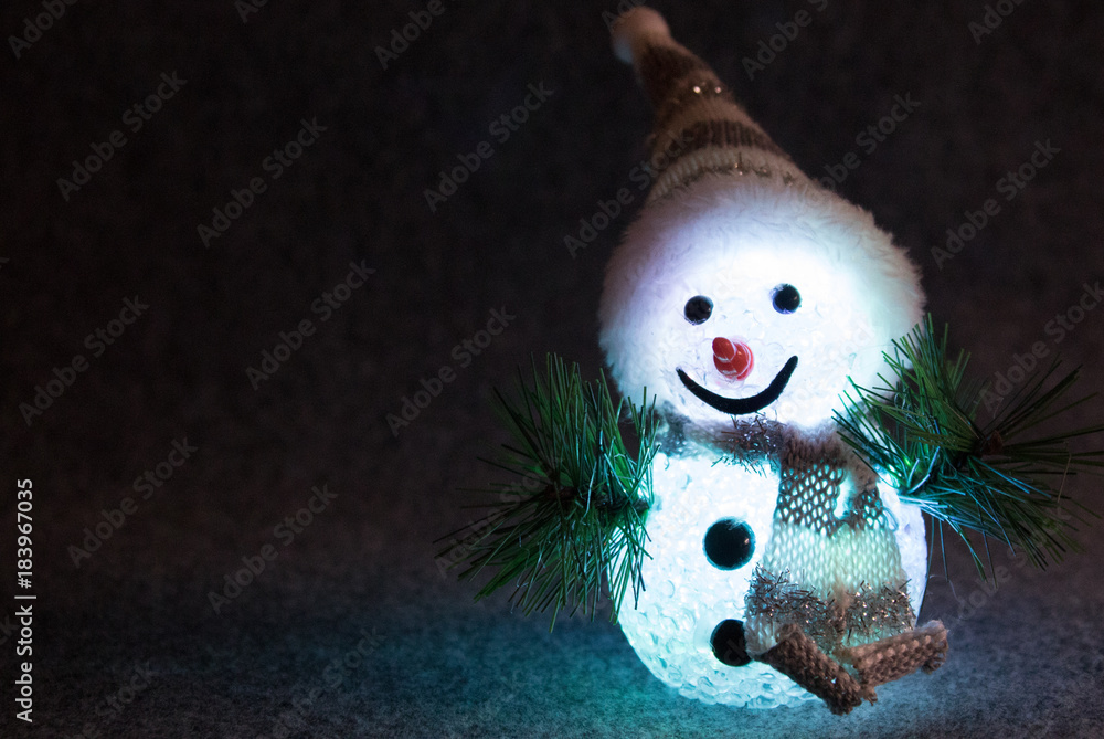 Fototapeta premium Funny snowman with friendly face lit in front of black background