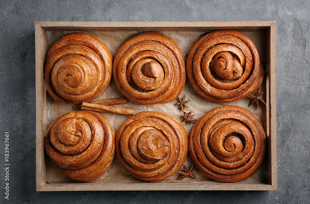 Fototapeta premium Wooden tray with sweet cinnamon rolls on table