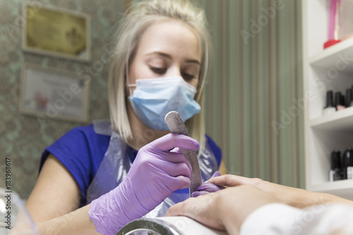 Cute girl master doing a manicure. In the beauty salon, a brunette girl is given a nail polish manicure on her hands. photo