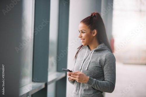 Attractive fit sporty girl typing on her phone before workout. Free Download Attractive fit sporty girl typing on her phone before workout. - GFXLoad