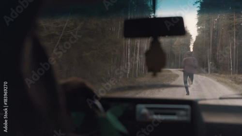 Man chased by a car through the forest road photo