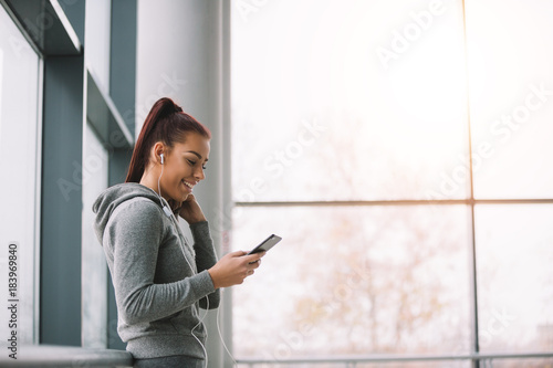 Sporty brunette typing on her phone and listening to the music before workout. Low angle view. Free Download Sporty brunette typing on her phone and listening to the music before workout. Low angle view. - GFXLoad