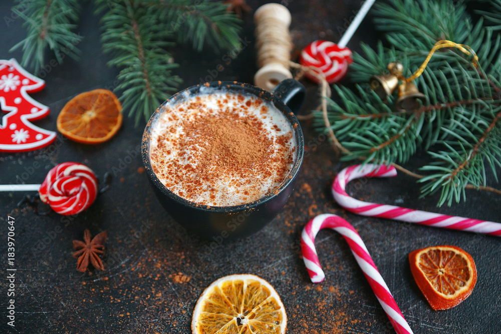 Christmas hot chocolate in a black cup with caramelized oranges, fir branches and candy cane on dark background, Selective focus Christmas hot chocolate in a black cup with caramelized oranges, fir branches and candy cane on dark background, Selective focus