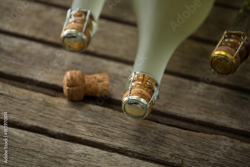Bottles of champagne and its cork on wooden surface