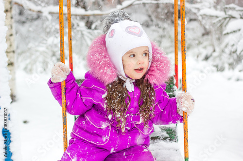 Little kid girl swinging on...