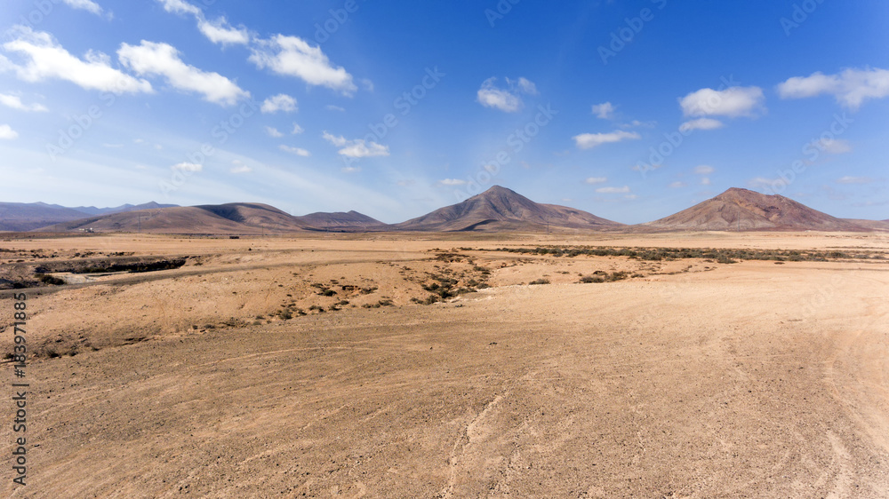 Volcanic mountains panorama with rocky desert terrain , against blue, cloudy sky, Fuerteventura, Canary Islands, Spain .