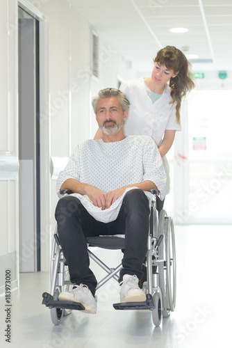 disabled man in wheelchair while a nurse is pushing him