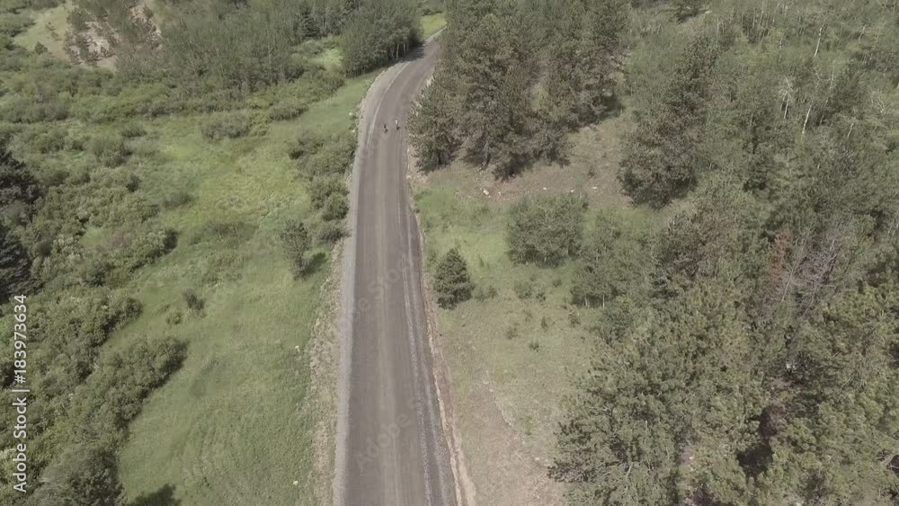 Aerial, cyclists ride on rural mountain road Aerial, cyclists ride on rural mountain road