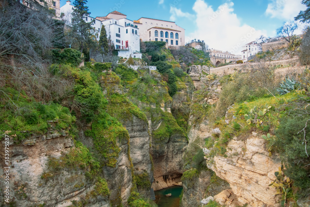 A view to Guadalevin river at El Tajo Gorge Canyon and traditional andalusian houses at the cliff in Ronda, a famous white village (pueblo blanco) in Malaga province, Andalusia, Spain.