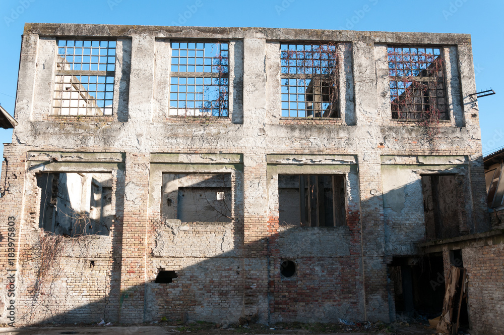 Old abandoned industrial factory warehouse building with brick wall broken windows and blue sky background