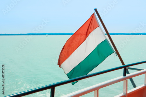 Hungarian flag at the cruise ship with bright light blue water of Balaton lake at the background Hungary.