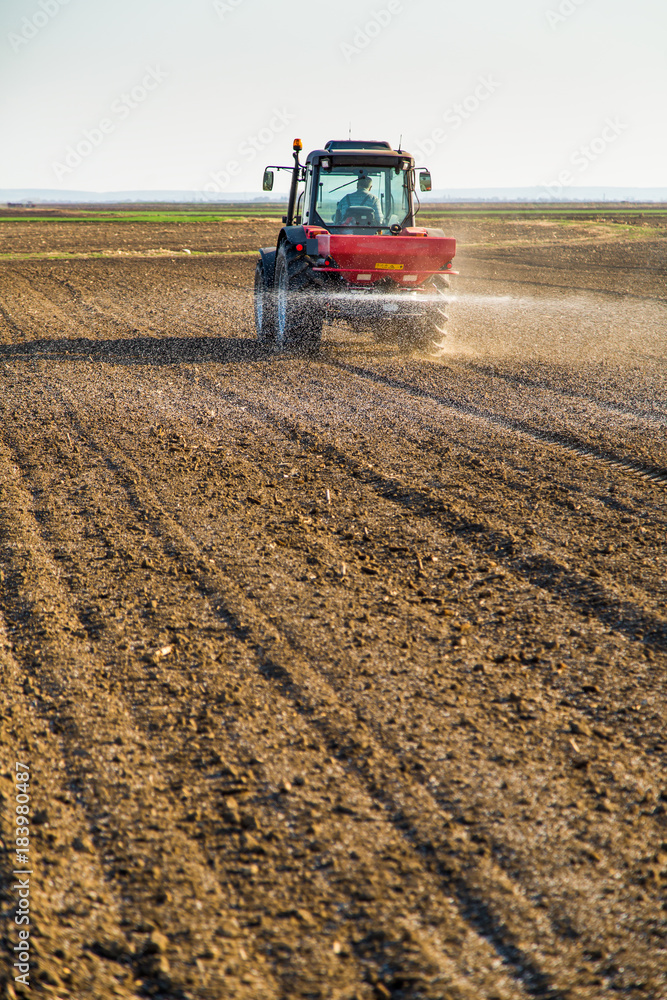 Obraz premium Farmer fertilizing arable land with nitrogen, phosphorus, potassium fertilizer