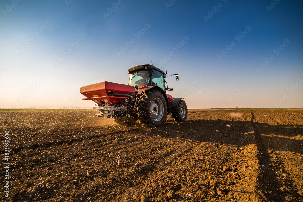 Fototapeta premium Farmer fertilizing arable land with nitrogen, phosphorus, potassium fertilizer