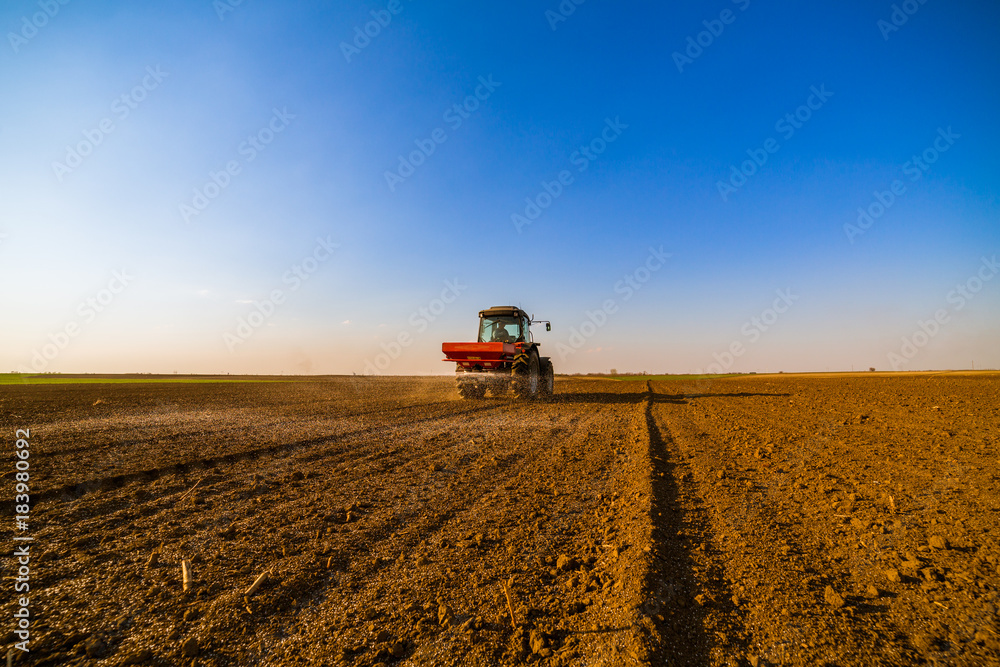 Fototapeta premium Farmer fertilizing arable land with nitrogen, phosphorus, potassium fertilizer