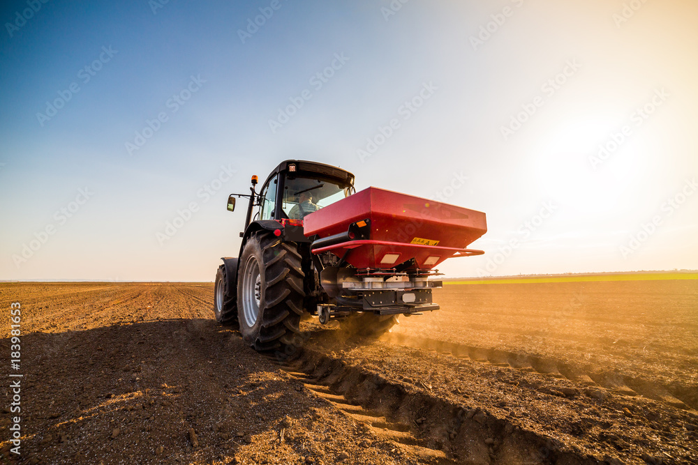 Fototapeta premium Farmer fertilizing arable land with nitrogen, phosphorus, potassium fertilizer