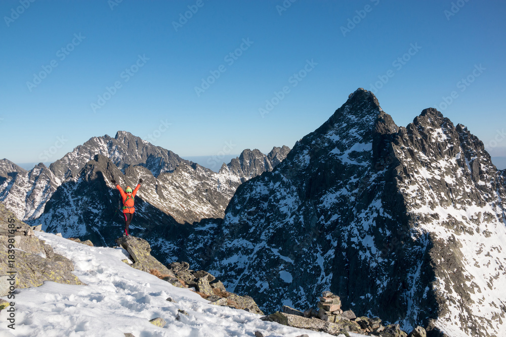 Successful woman backpacker with open arms enjoy the view on snow mountain peak.
