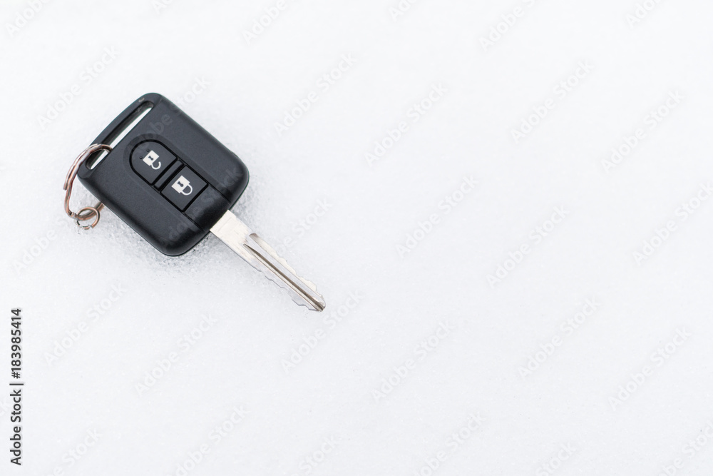 A black car key lies on the snow. A black car key lies on the snow.