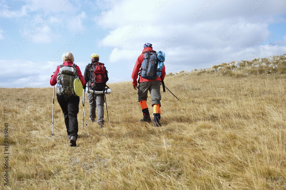 Group of tourists with backpacks on a mountain trail Group of tourists with backpacks on a mountain trail