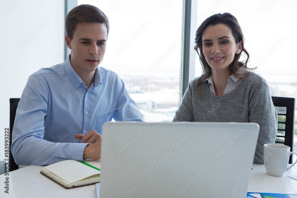 Male executive and female executive working over laptop Male executive and female executive working over laptop