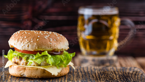 Hamburger on a wooden board against the background of a glass with beer