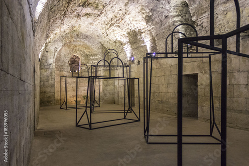 Cellars of Diocletian Palace in Spalato, with an art installation of bag silhouettes in iron material photo