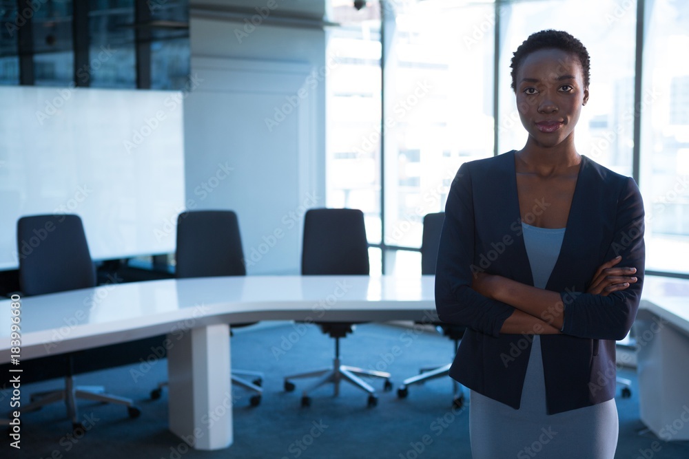 Female executive standing with arms crossed in boardroom