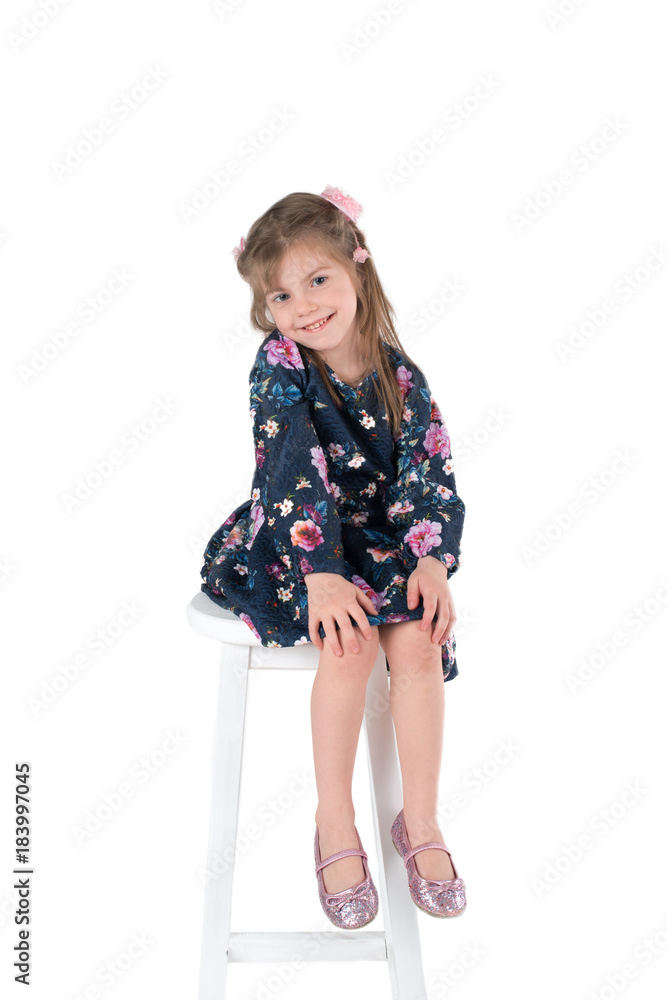 the girl in a dress sits on a high chair and smiles
