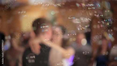 the bride and groom dance at a wedding banquet, soap bubbles fly. Blur, bokeh