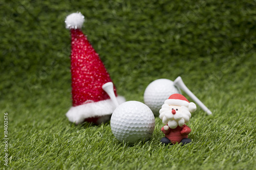Golf ball with Santa hat on green grass for golfer Christmas holiday