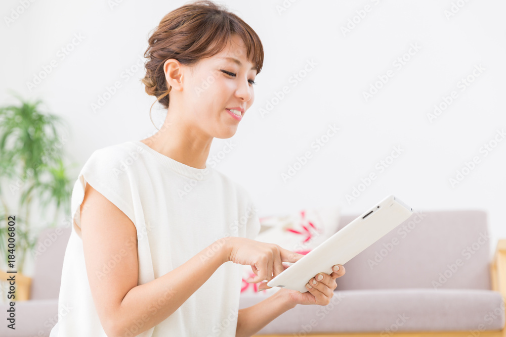 部屋でタブレットを見る女性