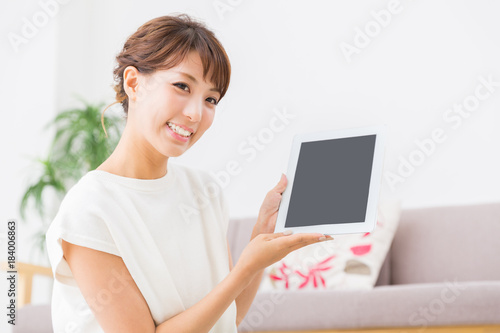 部屋でタブレットを見る女性