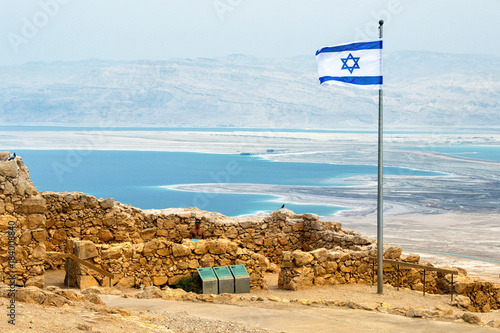 Israeli flag with the ruins on Masada with the Dead Sea on the background photo
