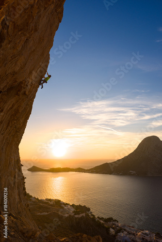 Man climbing a sttep overhanging wall at sunset photo