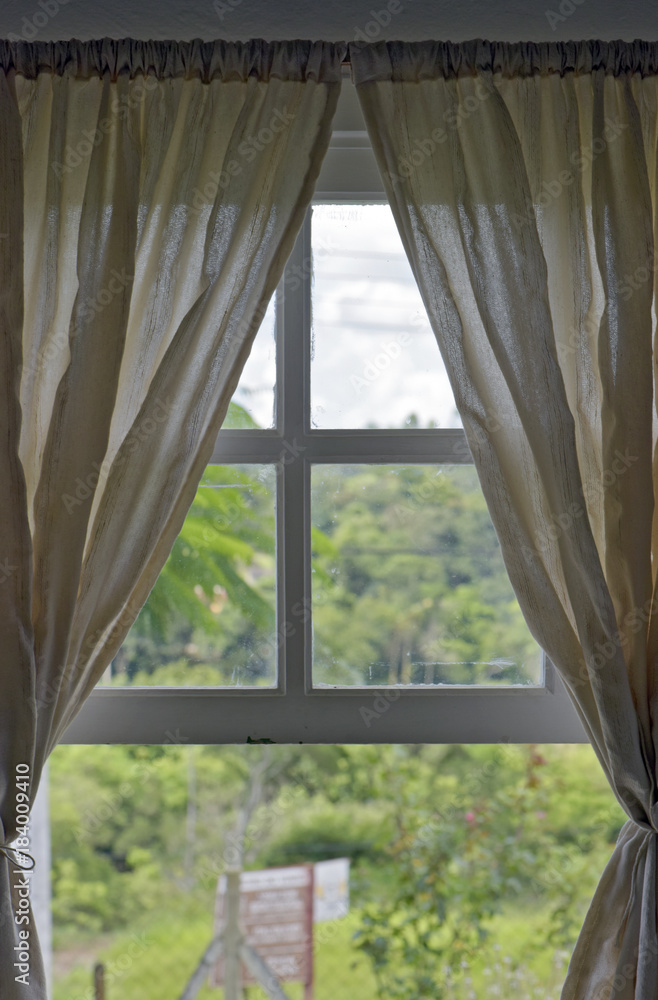 Fototapeta Otwórz okno do lasu z beżową zasłoną