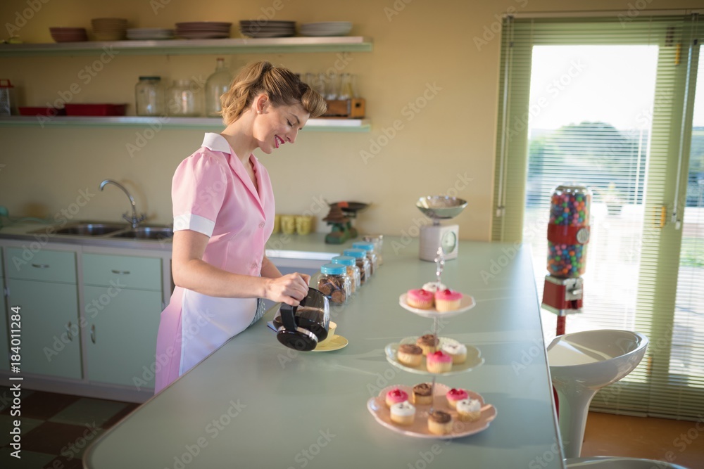 Waitress pouring black coffee in mug at restaurant Waitress pouring black coffee in mug at restaurant