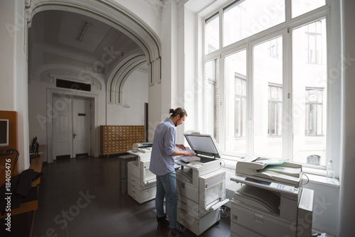 Male student using copymachine in public library